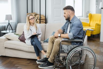 healthcare-worker-examining-man-in-wheelchair-at-home.jpg